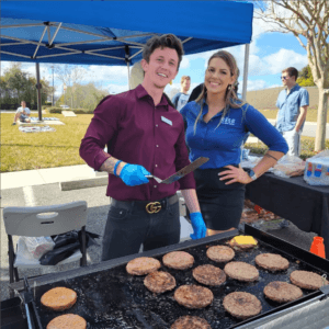 RISE Red Mountain luxury apartments in Birmingham staff members flipping burgers on a grill at an outdoor function